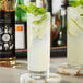 A glass of Twisted Alchemy simple syrup with lime and mint on a coaster.