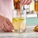 A person mixing a drink in an Acopa diamond cut cocktail stirring glass.