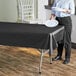 A woman standing next to a black plastic table covered with a white plate.
