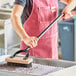 A person using a Choice stainless steel bristle grill brush to clean a metal surface.