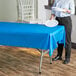 A woman standing next to a blue table with a white plate on it.