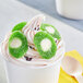 A cup of frozen yogurt with green Vidal Sour Gummy Kiwis on top.