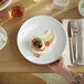 A person holding a Libbey white porcelain fruit bowl filled with food.