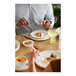 A man eating food on a Libbey white porcelain plate at a table.