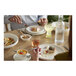 A group of people eating at a table with Libbey white porcelain saucers.