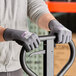 A person wearing Armor Guys heavy duty work gloves with black palm coating holding a metal bar.