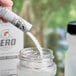 A hand pouring Gatorade Zero Sugar Glacier Cherry powder into a jar.
