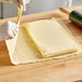 A person using a White Toque unsalted butter sheet to make pastry dough.