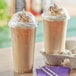 Two Choice clear plastic cups of coffee with whipped cream and dome lids.