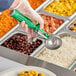 A person using a Fourté Green Thumb press disher with a green handle to serve food.