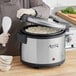 A woman using an Avantco non-stick pot to cook rice in a rice cooker.