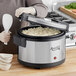 A woman using an Avantco electric rice warmer to make rice.