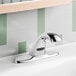 A close-up of a silver Delta touchless faucet on a white bathroom sink with a mirror in the background.