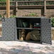 A Suncast grey outdoor patio storage cabinet with a door open and pillows and blankets inside.