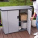 A woman opens a Suncast outdoor patio storage cabinet on a deck.