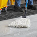A person mopping a floor with a Lavex White Rayon mop head on a blue pole.