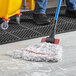 A person cleaning a floor with a Lavex Pro white rayon blend mop.