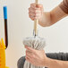 A man using a Lavex wooden mop handle to clean a floor.