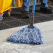 A person using a Lavex Blue Rayon mop to clean a floor.