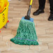 A person mopping a wood floor with a green Lavex Pro mop.