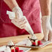 A person wearing gloves using an Ateco biodegradable pastry bag to prepare a dessert.