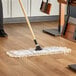 A Lavex white cotton looped end mop head on a wood floor.