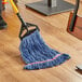 A person mopping a wood floor with a blue Lavex cotton blend mop.