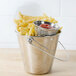 A stack of stainless steel round ribbed sauce cups filled with ketchup on a counter.