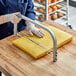 A person using an Ateco adjustable cake leveler to cut a cake.