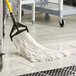 A person using a Lavex white rayon mop to clean a floor.