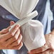 A person using an Ateco white pastry decorating bag clip to close a white pastry bag.