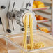 Estella #25 Spaghetti Alla Chitarra Pasta Die being used in a yellow pasta machine to make noodles.