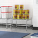 A Regency stainless steel dunnage shelf with cans of food on a wire mat.