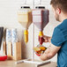 A man using an Asept countertop condiment pump to add ketchup to a burger.