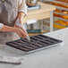 A person using a Pavoni Pavoflex silicone baking mold to make a dessert.