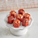 A white Pavoni candy mold with red chocolates in hexagon shapes.