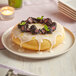 A Pavoni silicone baking mold with a donut with blackberries and white icing on top on a white plate.