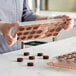 A woman holding a Pavoni round polycarbonate candy mold filled with chocolates.