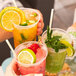 A set of three colorful iced drinks in clear plastic cups, each with a natural wrapped jumbo straw.