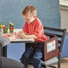 A child sitting in a Lancaster Table & Seating wooden booster seat at a table with a woman.