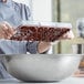 A person pouring chocolate into a Pavoni 3 compartment chocolate bar mold.