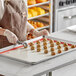 A woman in an apron using a Pavoni full size silicone baking mat to bake cookies.