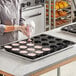 A person using a Pavoni Pavoflex Semi-Sphere Baking Mold to make cupcakes with pink frosting.