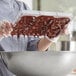 A woman pouring chocolate into a Pavoni chocolate bar mold.