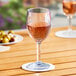 A Choice plastic wine glass filled with pink liquid on a table outdoors.