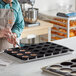 A man in an apron using a Pavoni Pavoflex Cilindro silicone baking mold to make chocolates.