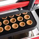 A gloved hand using a brown Pavoni Cookmatic Pastry / Tartlet Press to make tartlet shells.