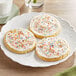 A Pavoni silicone baking mat with three cookies and milk on a plate.