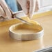 A person cutting a pastry with a Pavoni Progetto Crostate stainless steel tart ring using a knife.