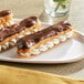 Two chocolate covered eclairs on a white plate with a Pavoni silicone baking mat.